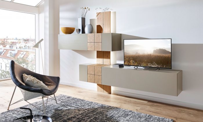 Photo d'ambiance mettant en scène un meuble TV avec des éléments muraux suspendus, dont un bar mural et une étagère. Un éclairage est dissimulé derrière la planche en bois brut.